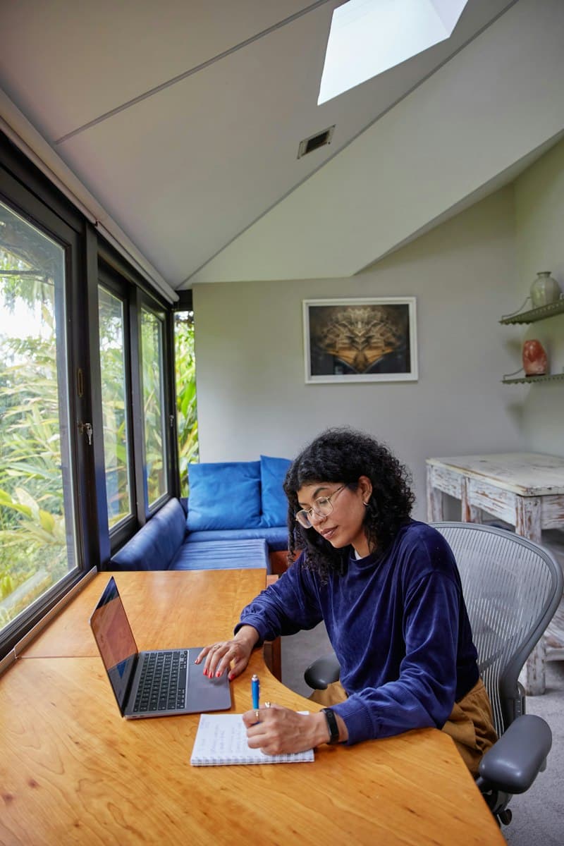 Woman studying on a laptop at a table by a window